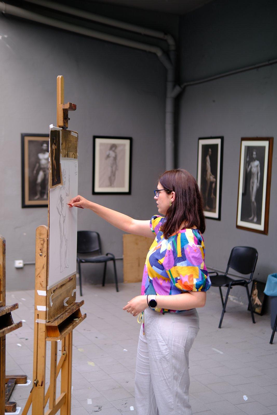 Tiana drawing at an easel in an atelier studio